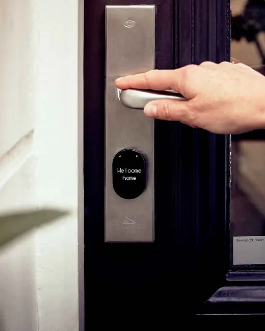 A hand opening a door with a modern lock