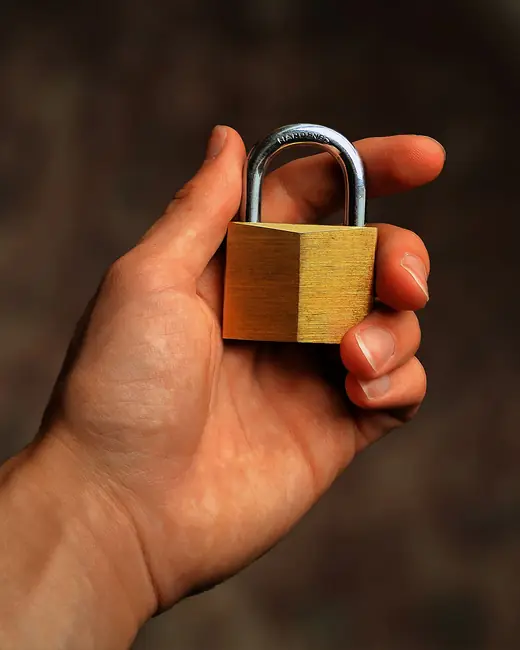 A brass padlock held in a hand