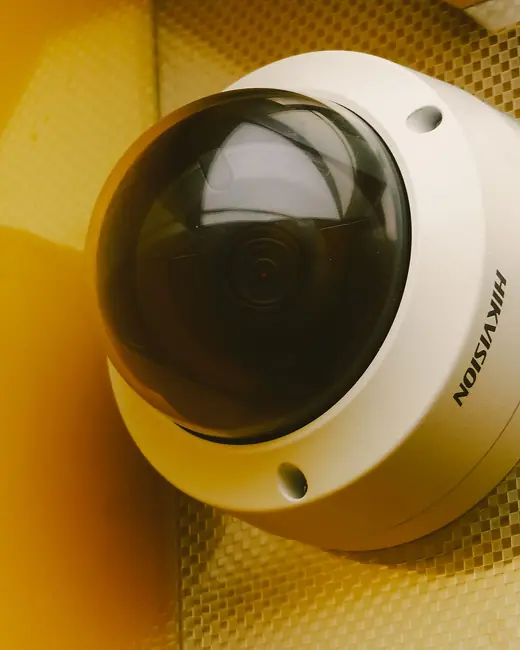 A dome security camera on a yellow wall
